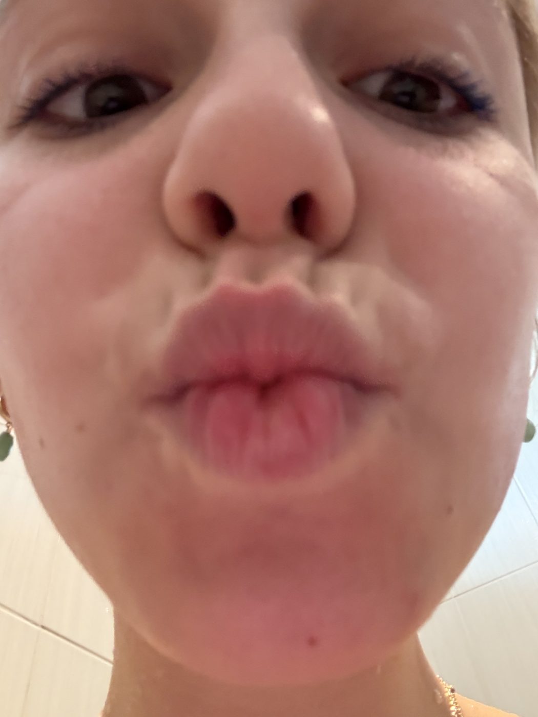 Très gros plan sur son visage collé à l'objectif, bouche en cœur.