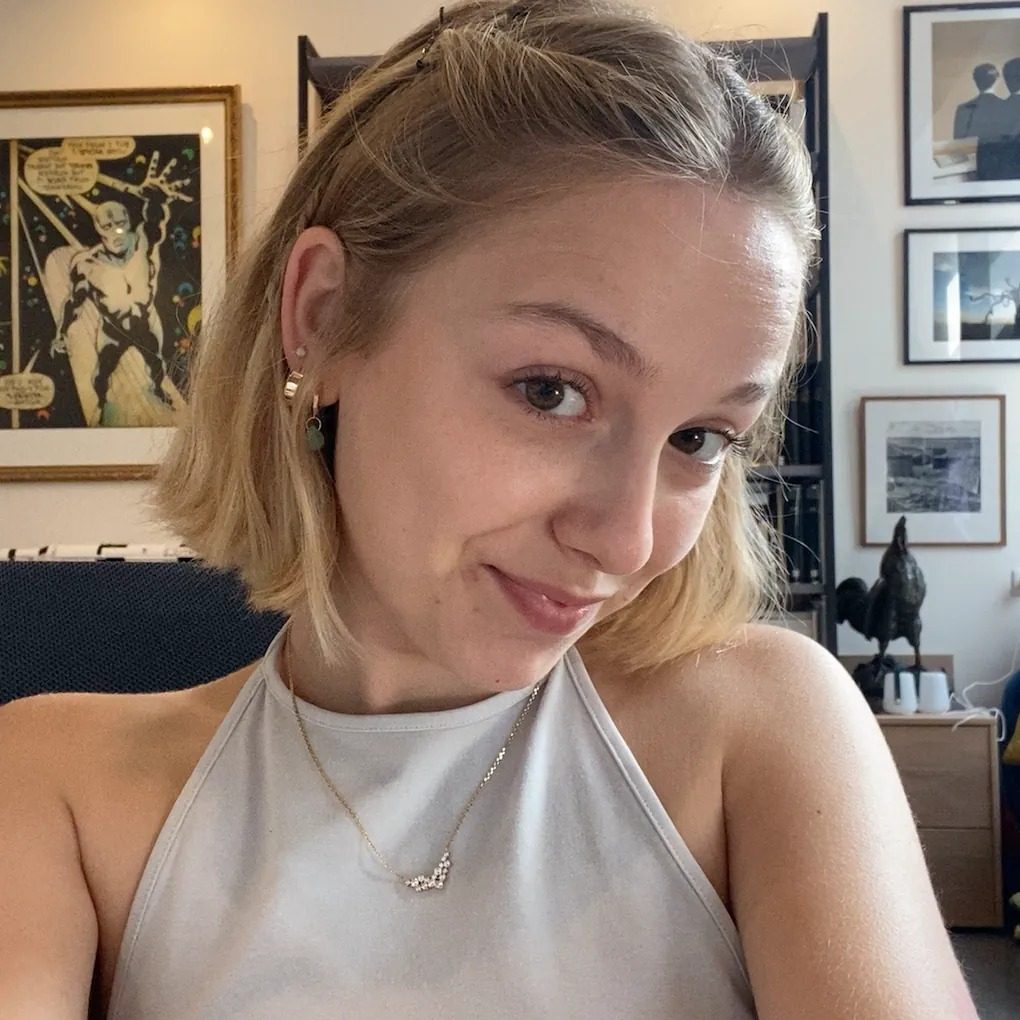 Selfie carré chez elle, sourire en coin, cadres de bande dessinée derrière.