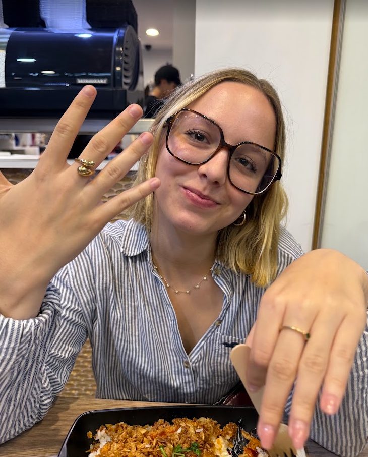 Attablée devant un plat, lunettes sur le nez, elle tend les deux mains vers l'objectif pour montrer une bague fine à son doigt.