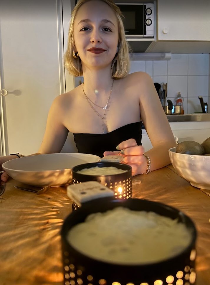 Dans une petite cuisine le soir, elle en haut noir derrière deux appareils à raclette où le fromage fond.