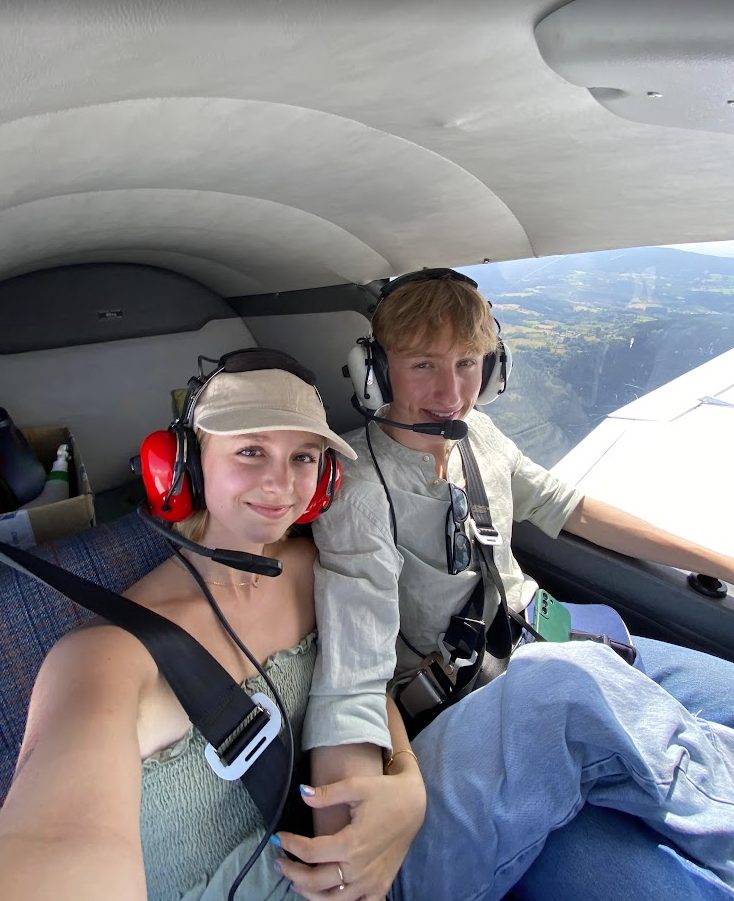 Tous les deux sanglés dans un petit avion, casques sur les oreilles, campagne visible par le hublot.